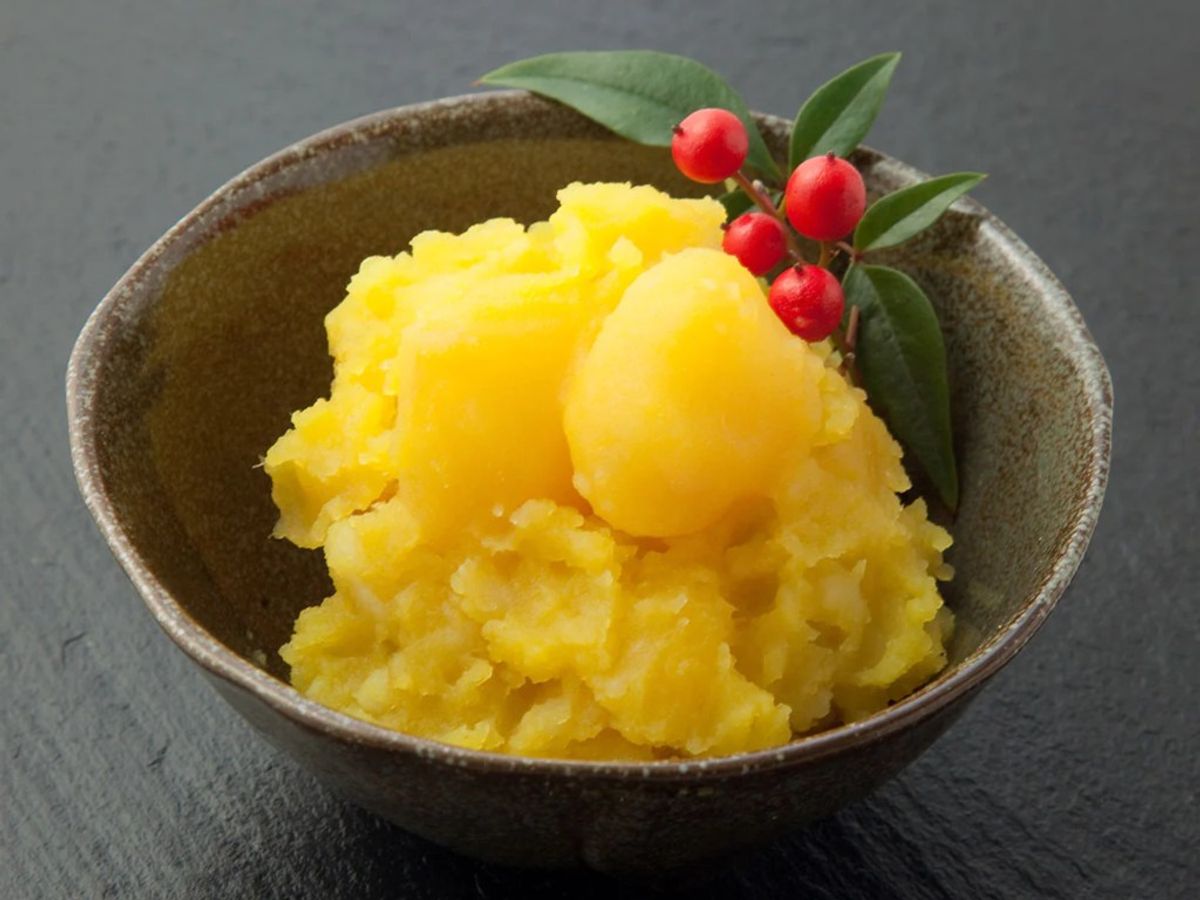 Yellow shaved ice dessert with red berries and green leaves in ceramic bowl