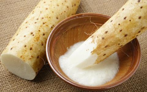 Daikon radish being grated into ceramic bowl on linen surface