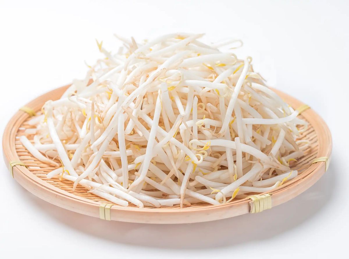 Bean sprouts on woven bamboo plate against white background