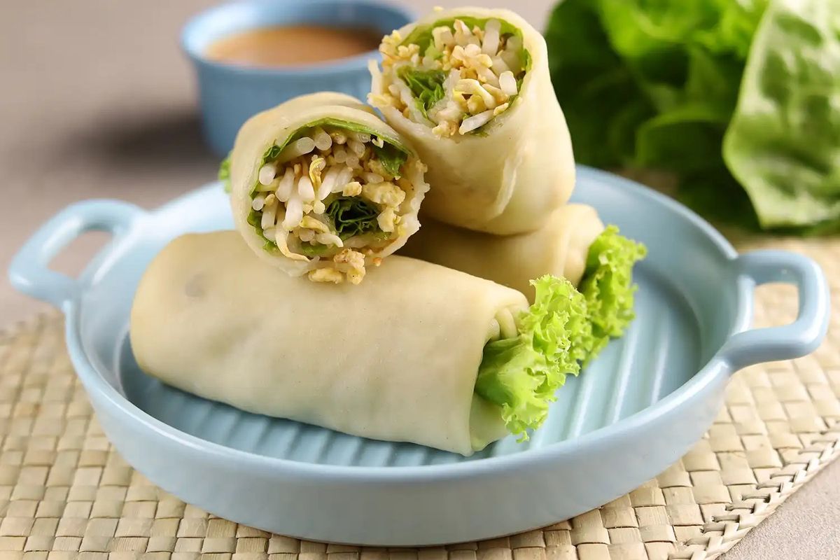 Rice paper rolls with lettuce and herbs served on blue plate with dipping sauce