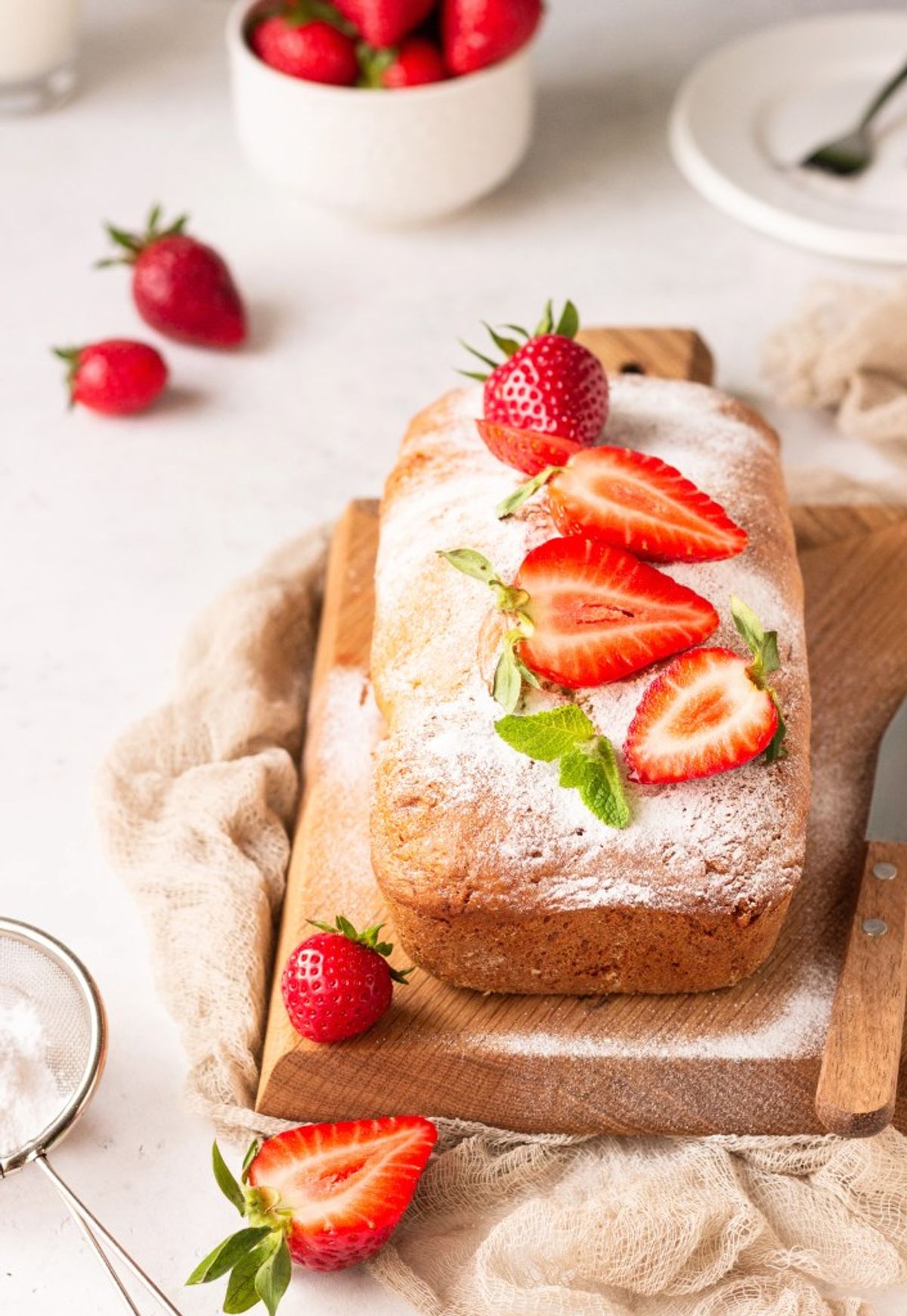 Strawberry pound cake dusted with powdered sugar on wooden board