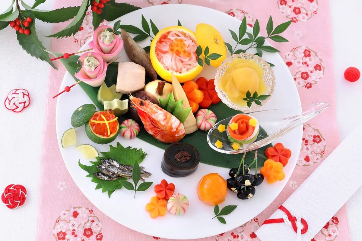 Colorful sushi platter with citrus, shrimp, and fresh vegetables on pink background