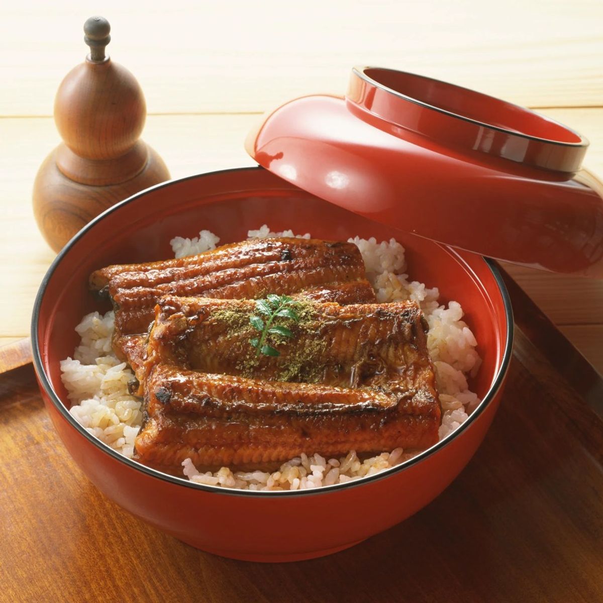 Unagi donburi with glazed eel over steamed rice in red lacquer bowl with lid