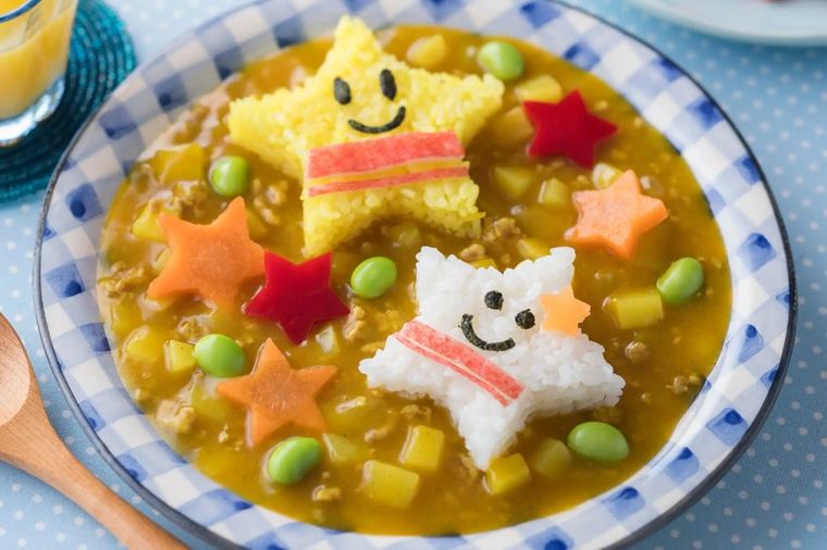 Decorative children's soup with cute character-shaped rice and vegetable stars in broth