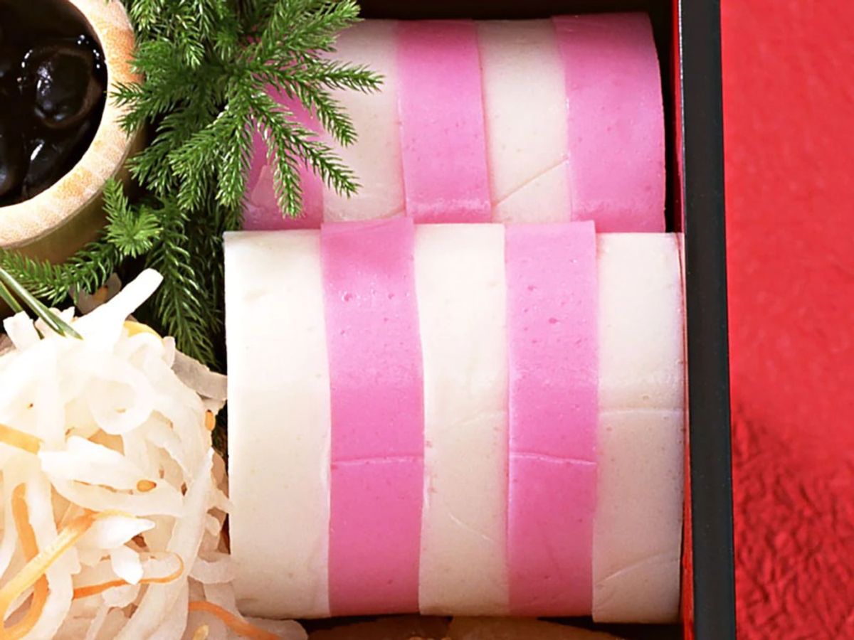 Pink and white striped wrapped mochi or rice cakes in decorative gift box with greenery