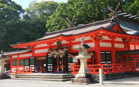 Traditional Japanese Shinto shrine with bright red architecture and ornamental details surrounded by trees