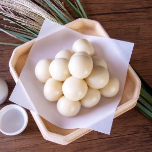 White mochi dumplings arranged in wooden basket with pink paper and dried grass decoration