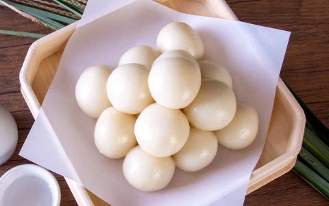 White mochi dumplings arranged in wooden basket with pink paper and dried grass decoration