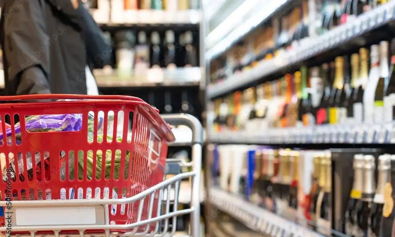 Red shopping basket in supermarket aisle with blurred product shelves in background