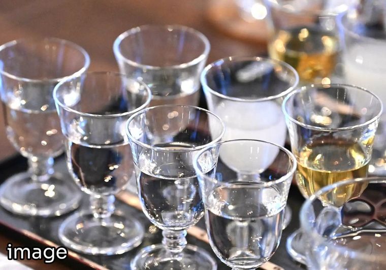 Multiple clear glass cups containing various liquids and spirits on table