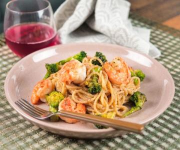 Shrimp and broccoli pasta with red wine on patterned placemat