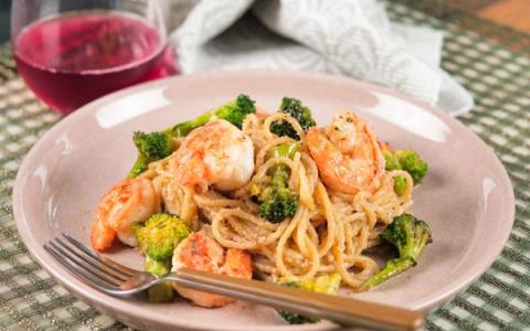Shrimp and broccoli pasta with red wine on patterned placemat