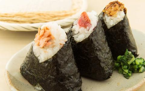 Three sushi hand rolls wrapped in nori with seafood and rice toppings, garnished with green onion
