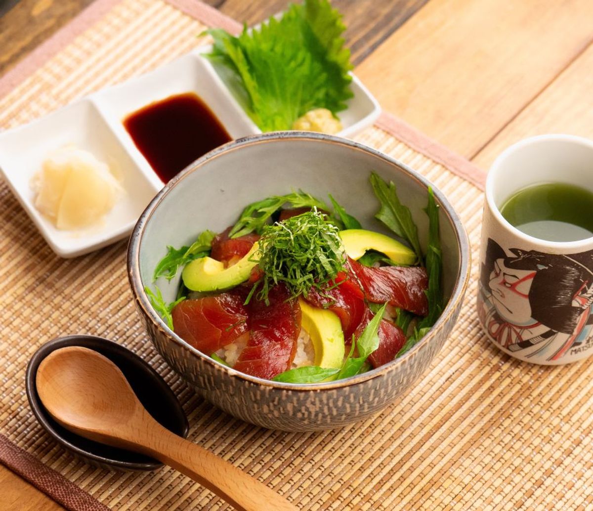Maguro donburi bowl with avocado, cucumber, and shiso, served with soy sauce and green tea