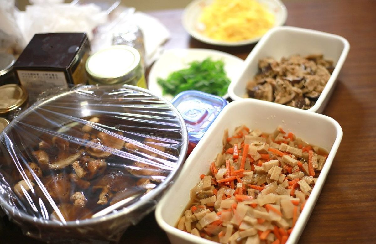 Japanese meal prep spread with covered dish, vegetables, meat, and side dishes arranged on table