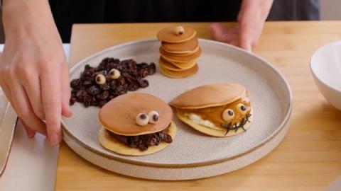 Creative pancake art with chocolate spread and candy eyes arranged on beige plate