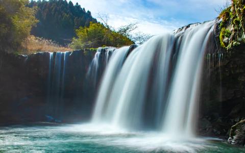 Scenic waterfall with turquoise water and forested mountains in natural landscape