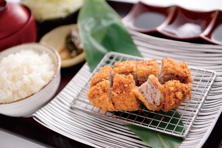 Tonkatsu breaded pork cutlets served with rice and green leaf garnish on striped plate