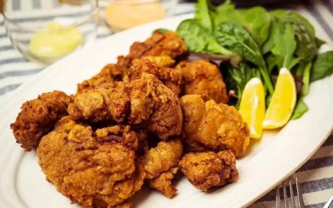 Fried chicken plate with fresh mint, lemon wedges on white dish