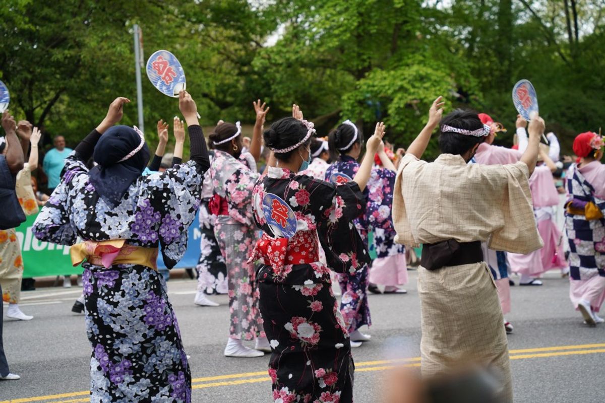 Japanese festival parade with participants wearing colorful yukata and holding fans outdoors