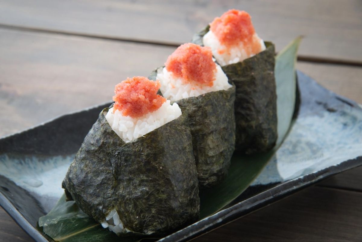 Three pieces nigiri sushi topped with ikura (salmon roe) on nori, served on slate plate