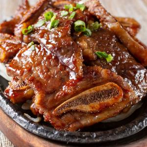 Glazed chicken wings with green onions on cast iron plate, Asian style