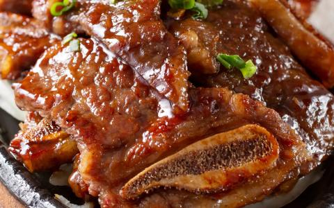 Glazed chicken wings with green onions on cast iron plate, Asian style