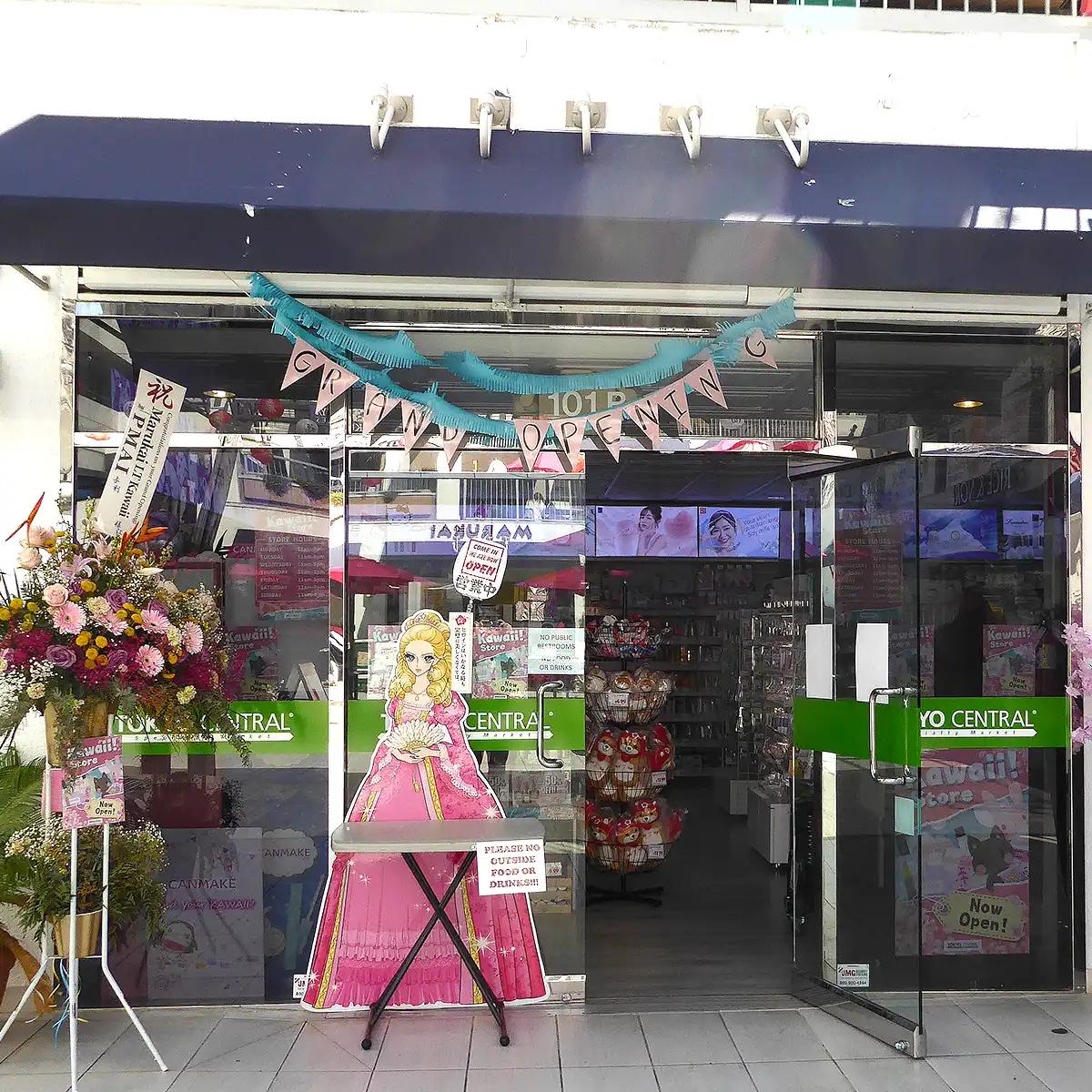 Japanese grocery store storefront with pink decorations, anime character display, and flower arrangements