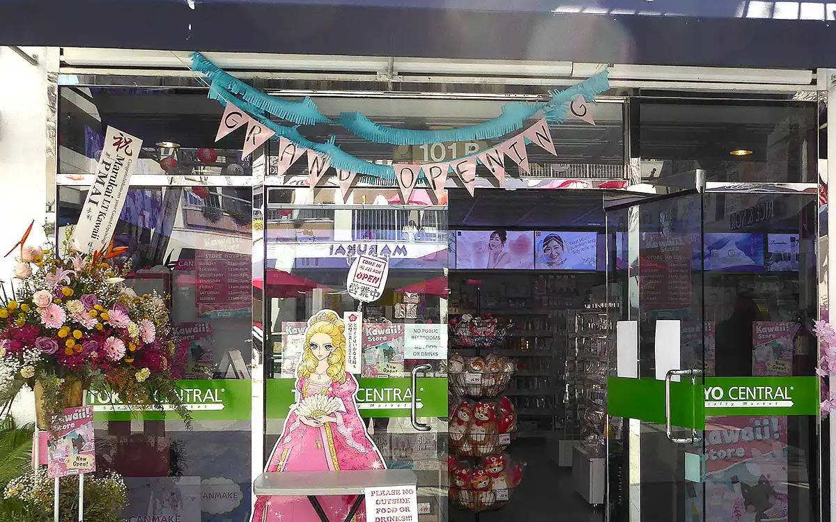 Japanese grocery store storefront with pink decorations, anime character display, and flower arrangements